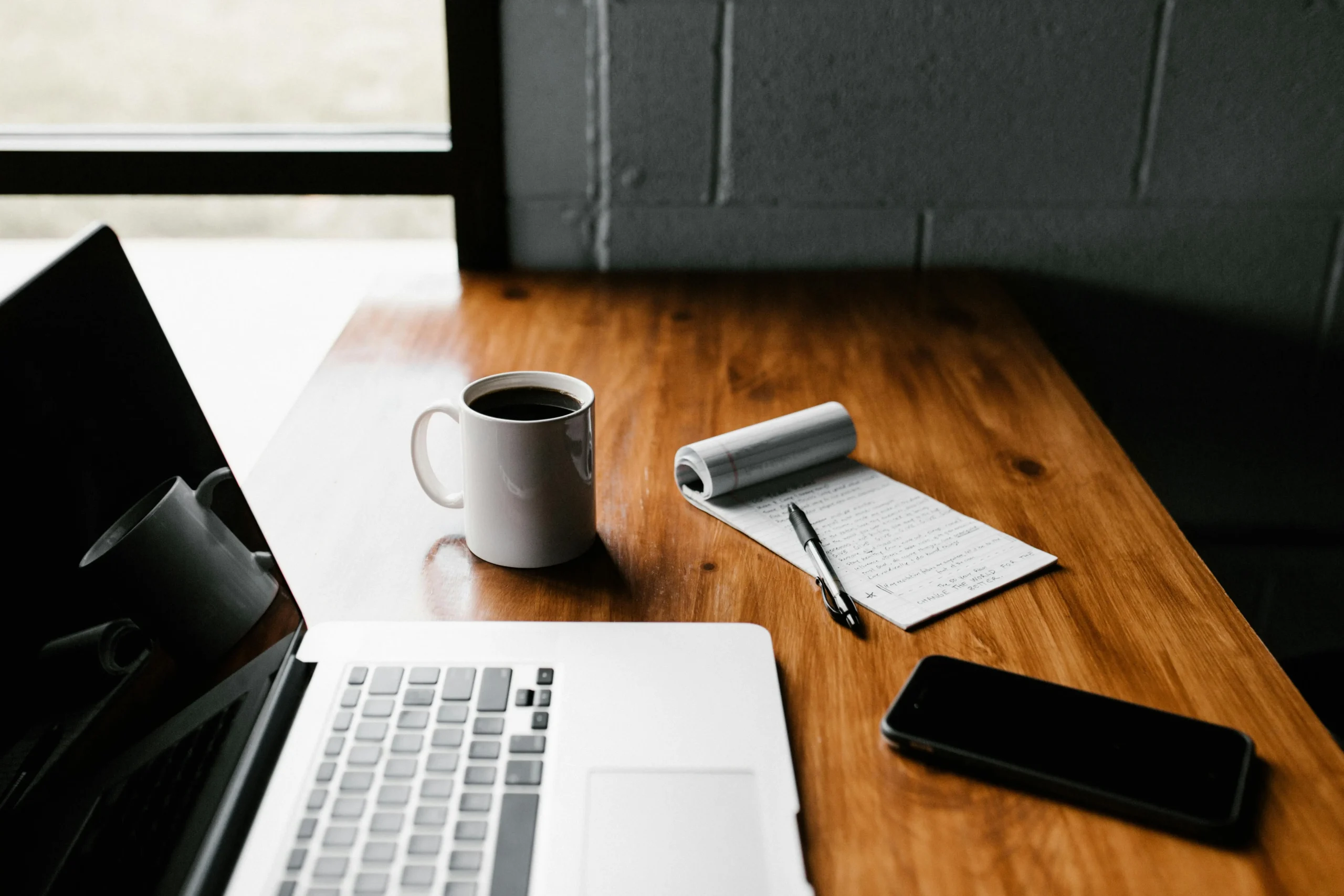 A minimalist workspace with a laptop, coffee mug, and notepad — representing streamlined processes like one-click checkout in modern e-commerce.