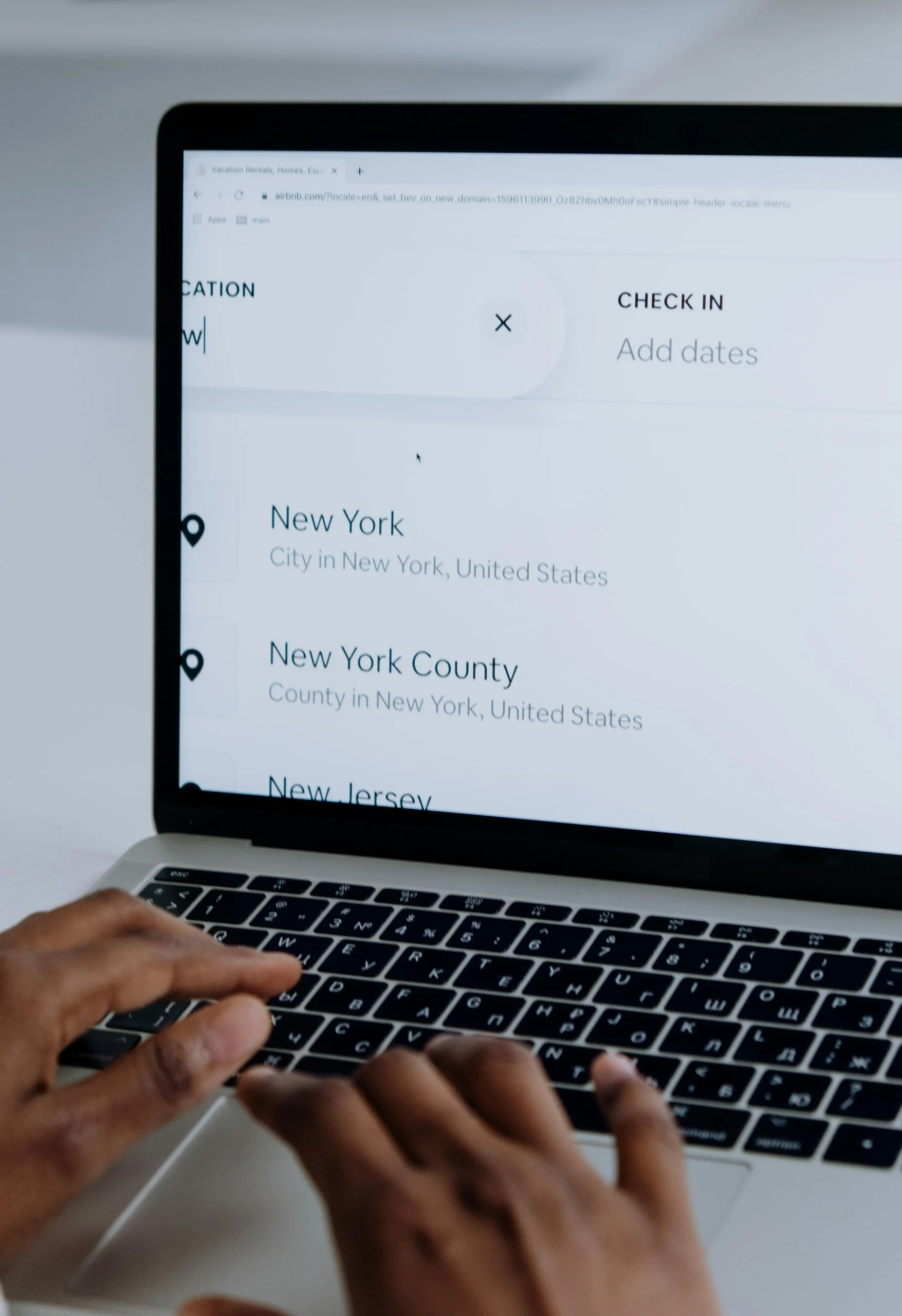 Person using a laptop to search for New York on a travel booking website, showing trusted user interface design