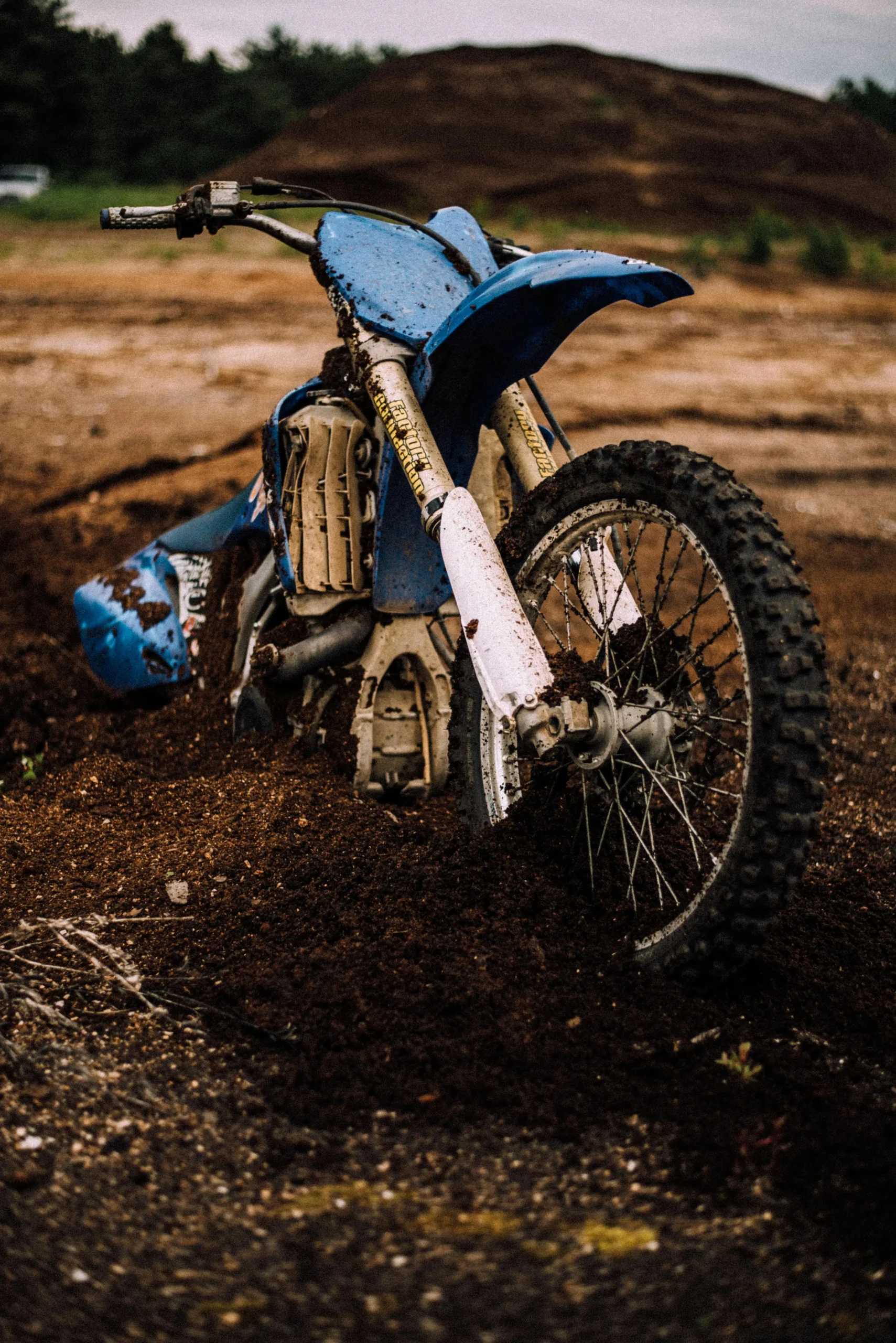"Damaged dirt bike stuck in muddy terrain, symbolizing a potential motorcycle accident and grounds for legal compensation."