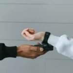 A shopper uses a smartwatch for contactless payment at a terminal, illustrating modern digital payment habits among Gen Z.