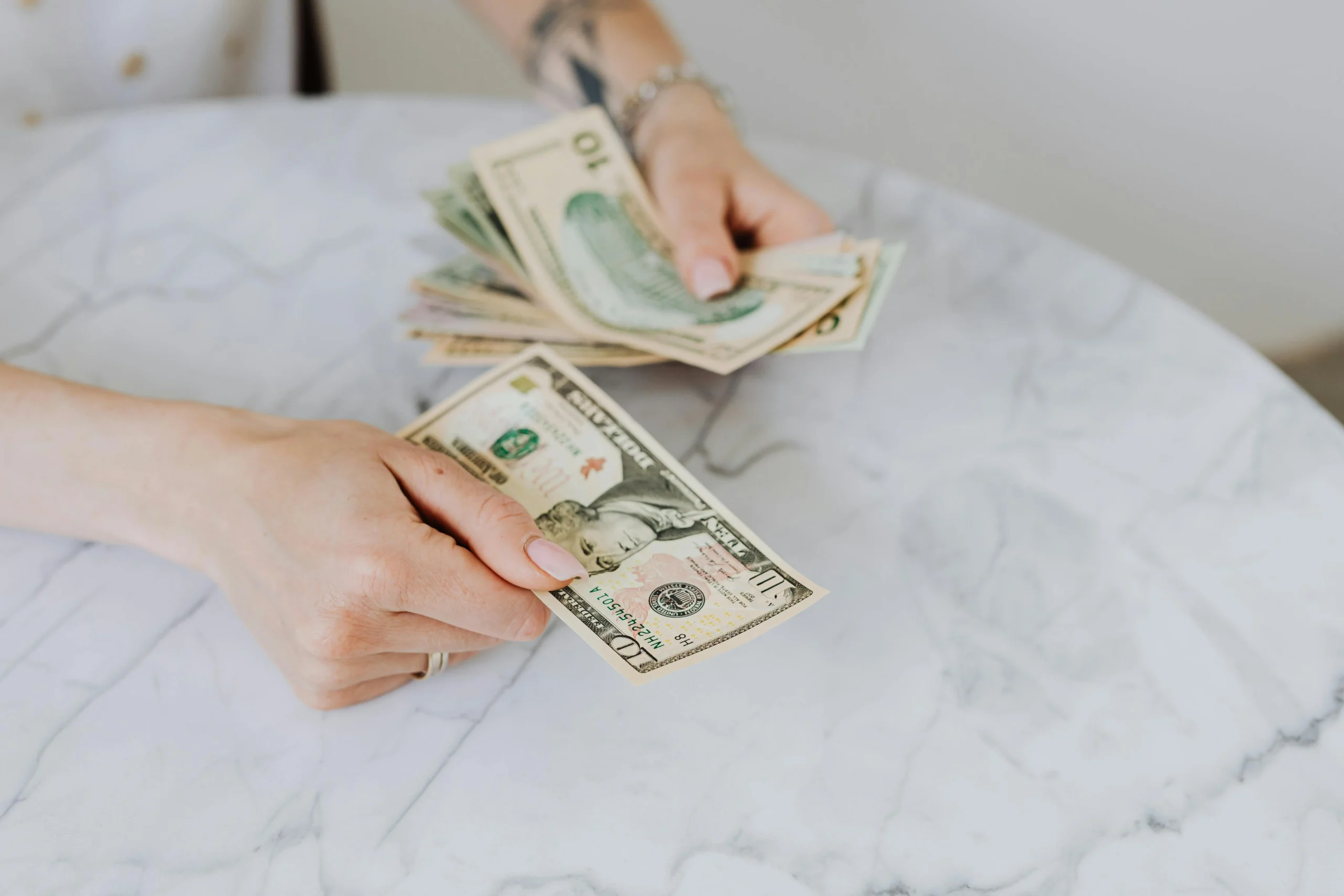 Close-up of a person counting U.S. dollar bills, representing traditional payment methods contrasted with Buy Now, Pay Later options.