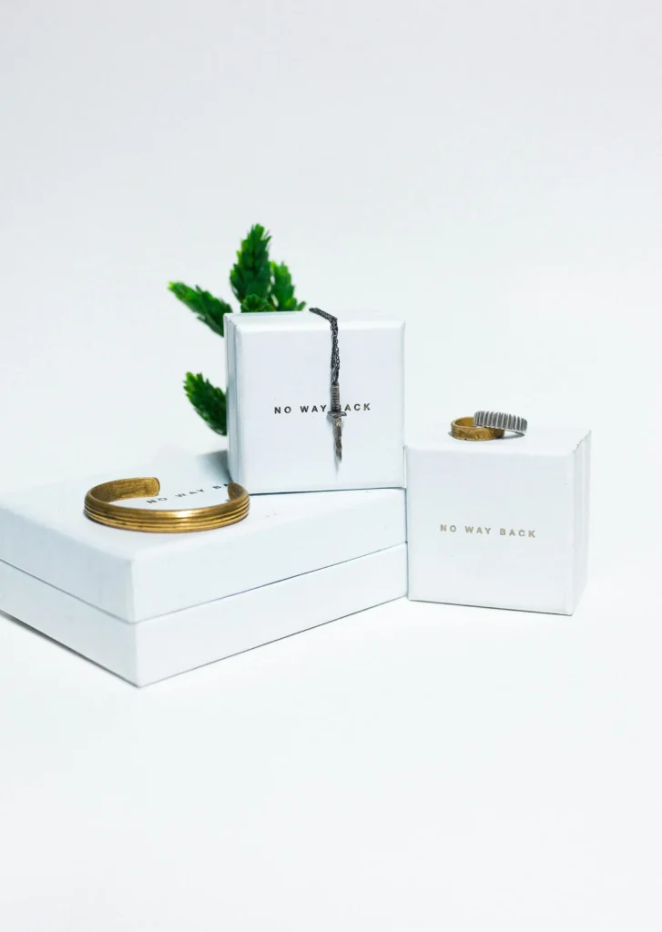 Elegant white boxes with minimalist branding and stylish bracelets, representing high-end product packaging for a distinct online brand.