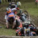 Motorcyclists involved in a muddy off-road crash with bikes and riders on the ground, illustrating the aftermath of a motorcycle accident.