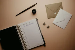 Open planner with a "New Year's Resolutions" to-do list surrounded by envelopes, a fountain pen, and decorative star earrings on a soft beige background — symbolizing shopper intent and planning behavior.