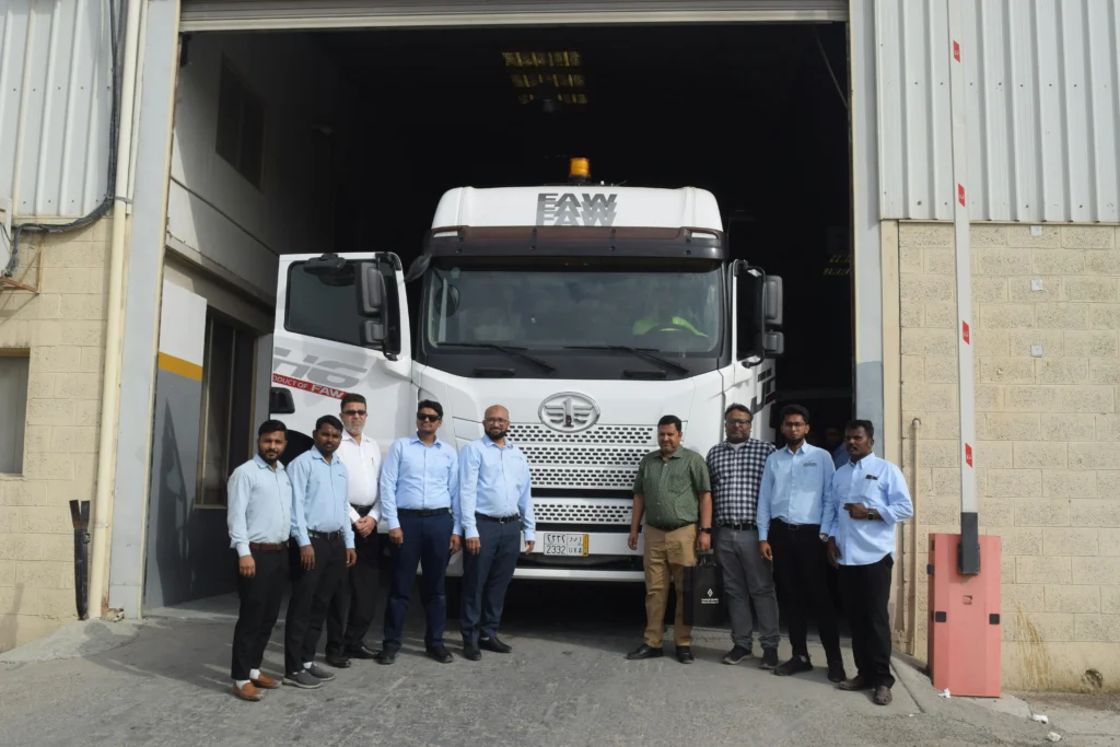 Group of men standing in front of a large commercial truck at a loading dock, representing the logistics and personnel involved in trucking operations relevant to accident claims