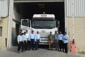 Group of men standing in front of a large commercial truck at a loading dock, representing the logistics and personnel involved in trucking operations relevant to accident claims