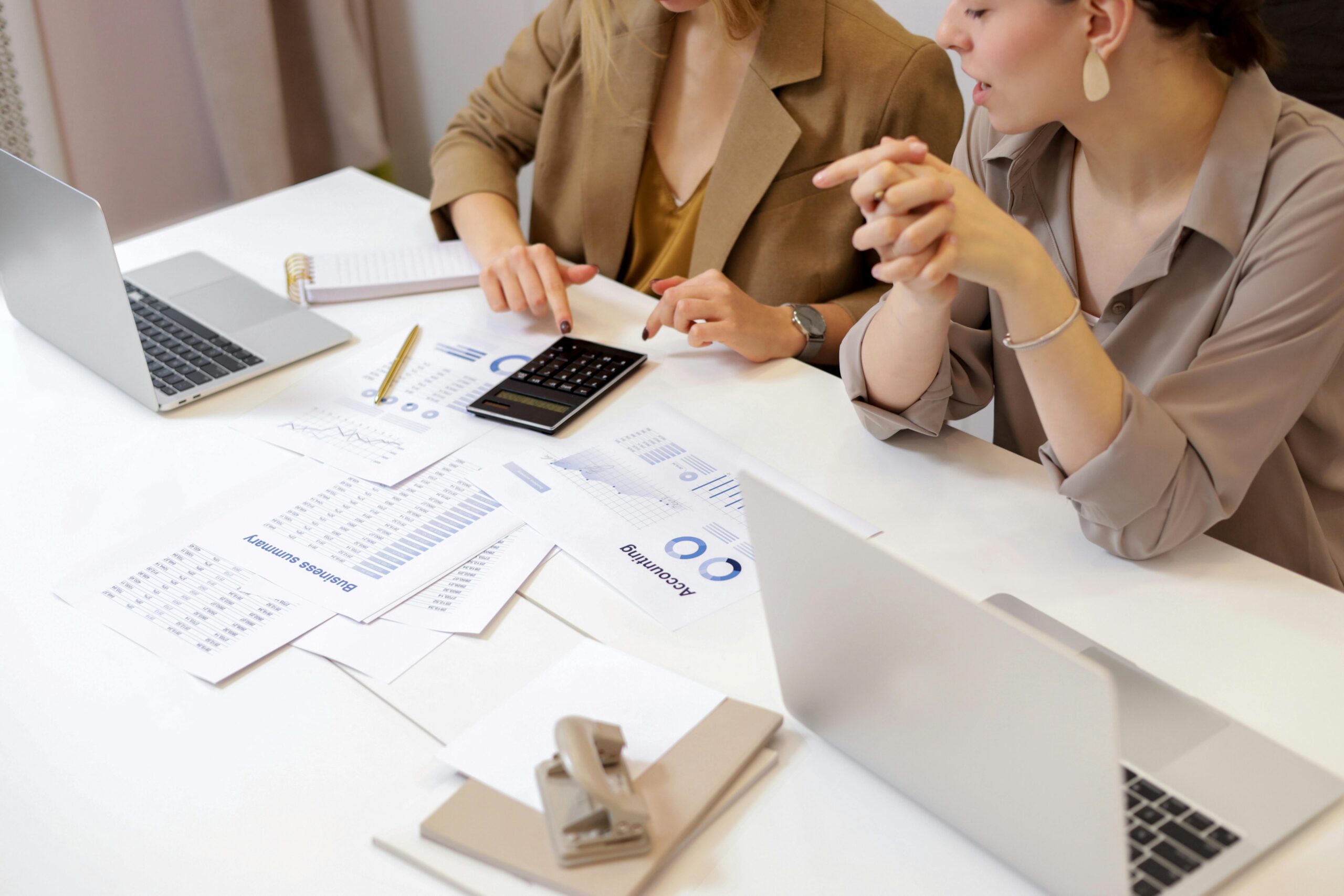 Professionals reviewing reports on laptops and calculator, symbolizing the emerging jobs market worldwide.