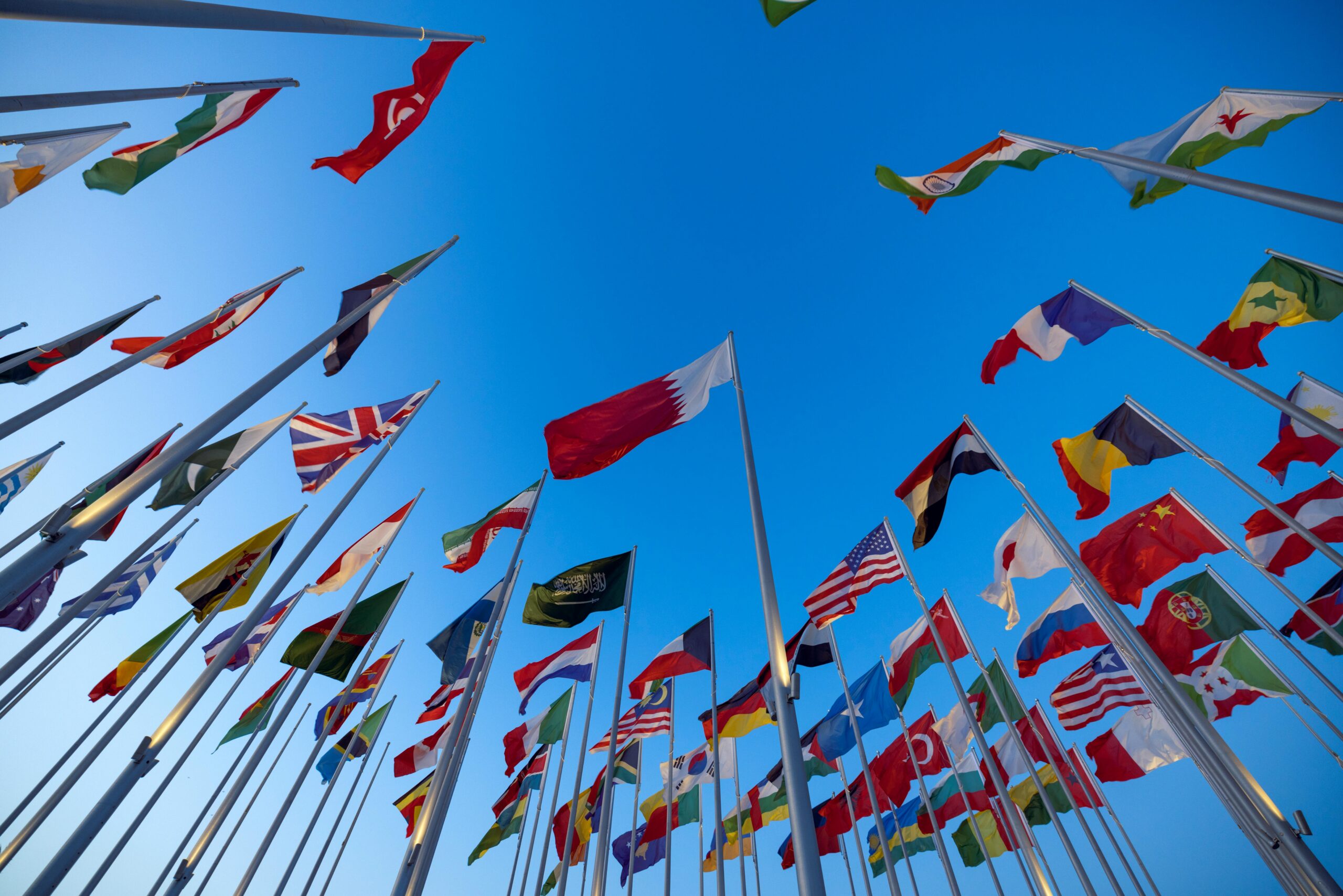 “Multiple national flags representing different countries where international students can study in English-speaking universities without IELTS requirement.”