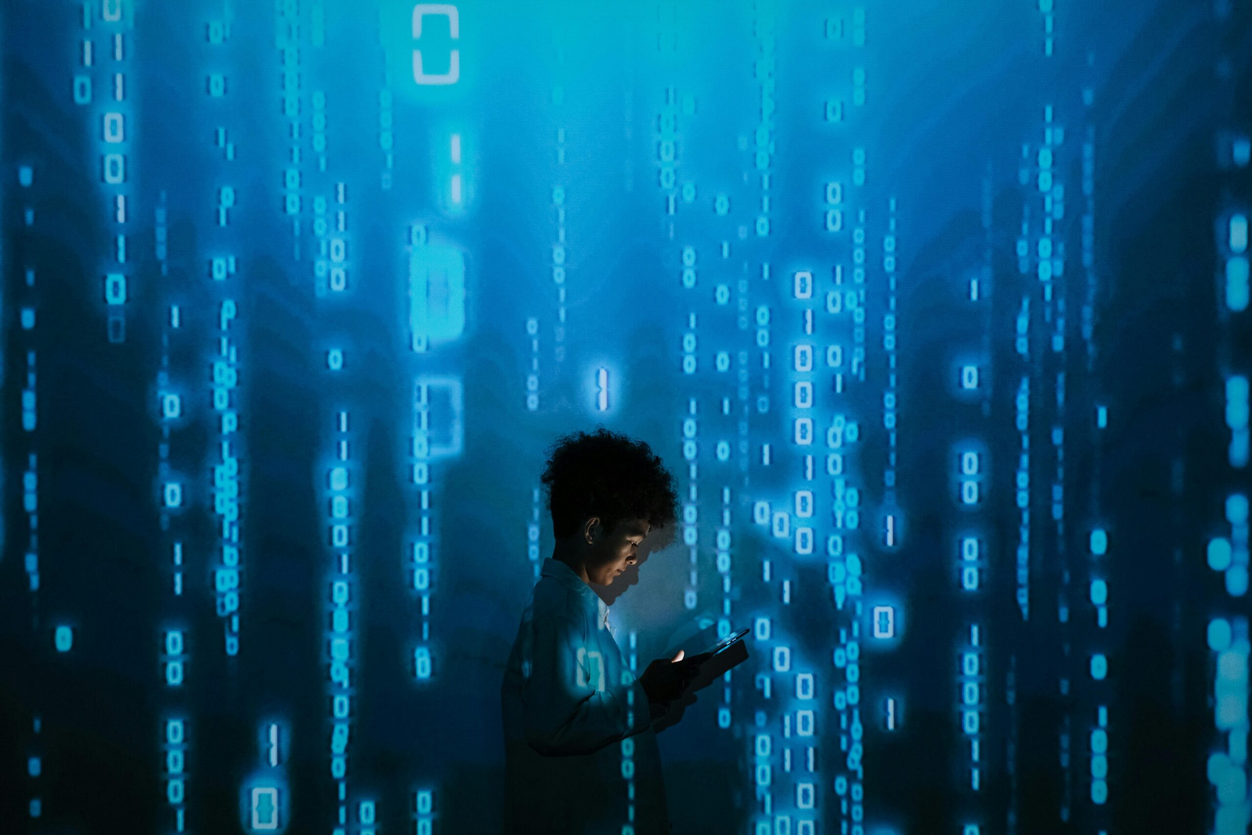 Young person using a tablet surrounded by digital binary code, symbolizing the future of jobs and essential tech skills in the AI-driven era of 2025.